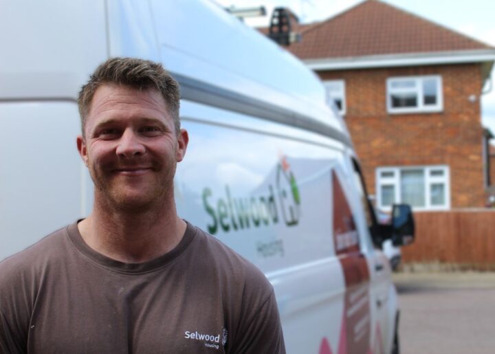 Luke Mead, one of Selwood Housing's multi-skilled plumbers, standing beside a Selwood Housing van near a house.