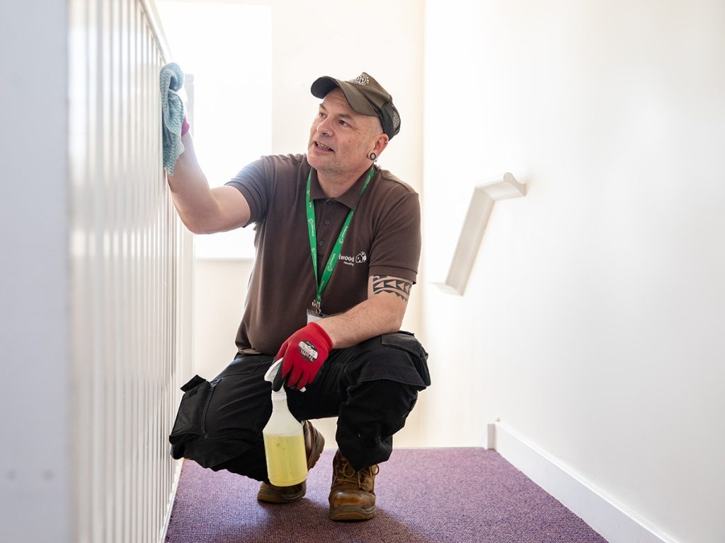 Selwood Housing neighbourhood caretaker Lance cleaning banister in communal hallway