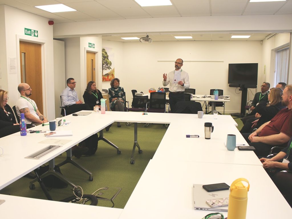 Barry Hughes talking to group of staff in meeting room at Selwood Housing office cmi qualification selwood housing