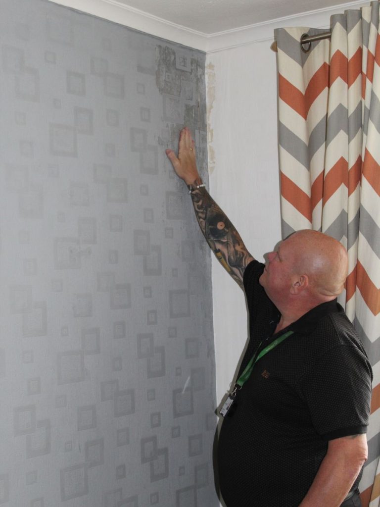 Jason Morris assessing a damp patch on the wall in a customer's home.