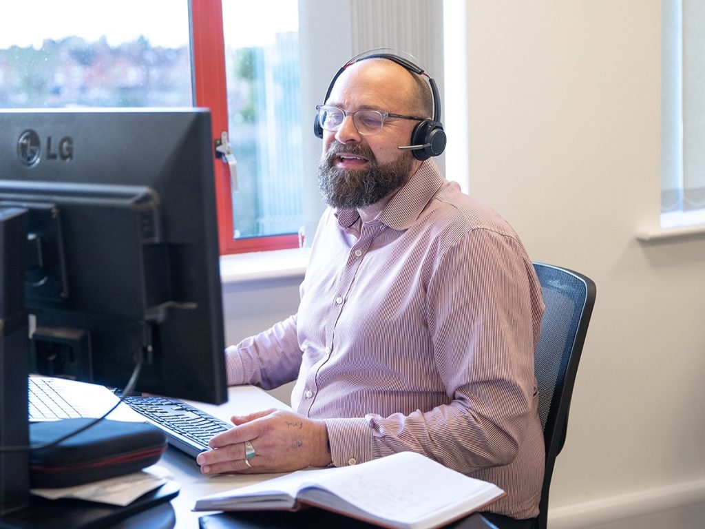 Neighbourhood manager, Mike Grizzell, speaking with a customer over the phone in the office