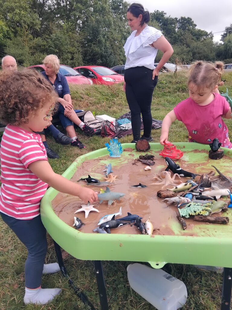 Two children enjoy playing with a sensory activity of sand, water and sea creatures.