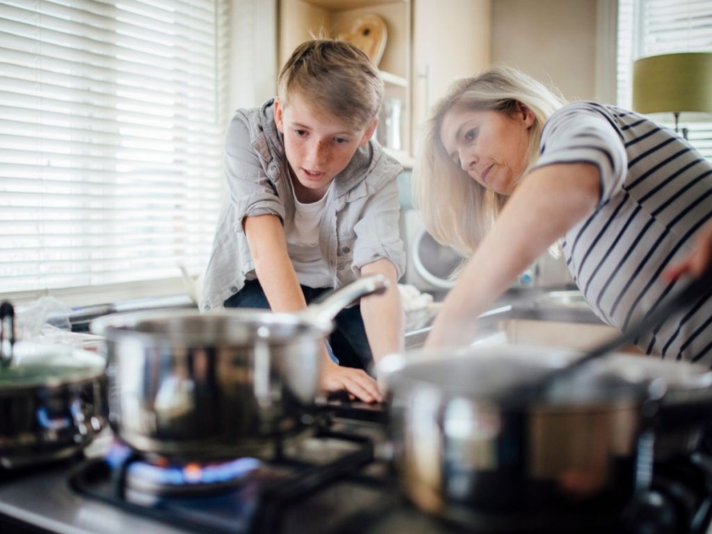 Mum and son cooking dinner on gas stove