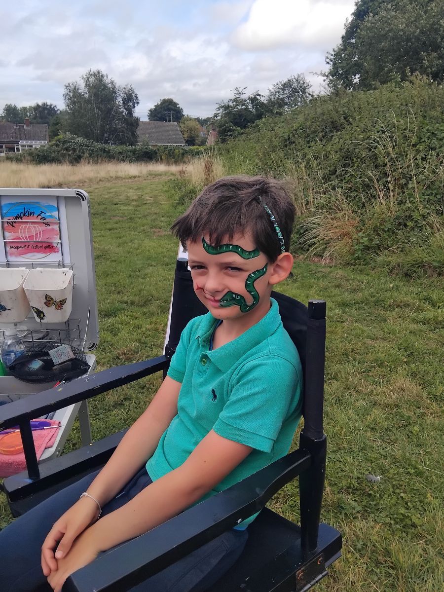 A boy with a snake face painting enjoying the family fun day