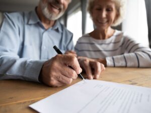 Two people signing documents at a table