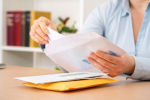 A person opening a letter from a white envelope