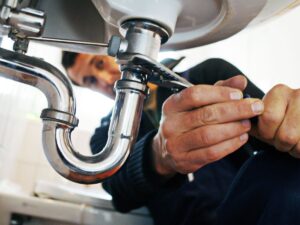 Plumber fixing pipes beneath a sink