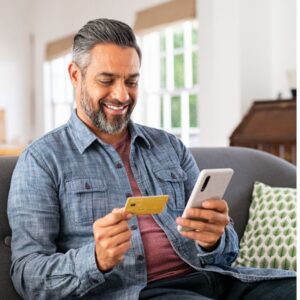 Man on sofa using a debit card and phone